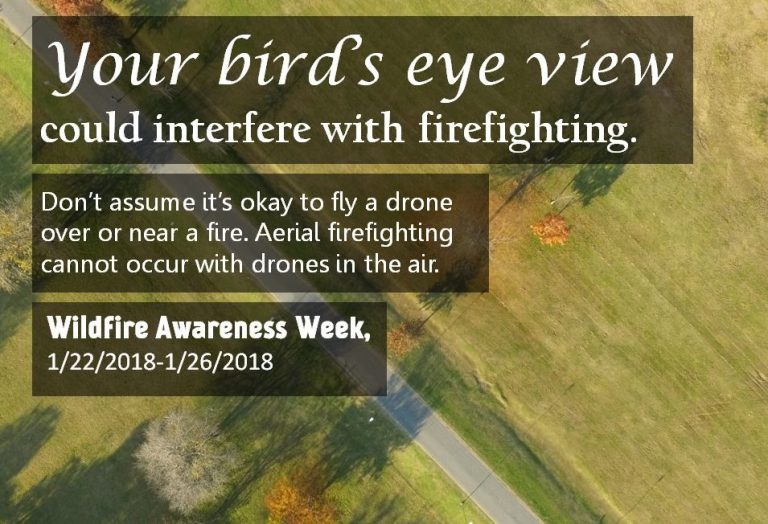 Aerial view of a grassy field with trees and a road, overlaid with text warning that flying drones near fires can interfere with firefighting, promoting Wildfire Awareness Week 1/22/2018-1/26/2018.